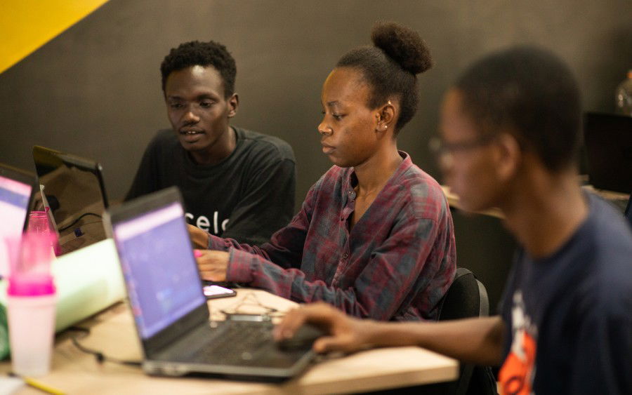 A group of young people are working on laptops